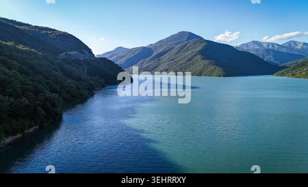 ZHINVALI, GEORGIA - 14 AGOSTO 2024: Un drone aereo cattura le spettacolari acque turchesi del bacino Zhinvali circondato da lussureggianti montagne verdi. Il massiccio bacino idrico, situato lungo la Georgian Military Highway, è una tappa panoramica molto apprezzata dai viaggiatori e dagli ecoturisti. Foto Stock