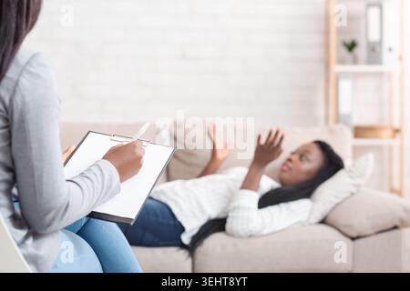 Giovane donna nero sdraiato sul lettino in corrispondenza dello psicoterapeuta Foto Stock