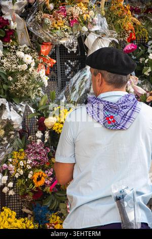 VITORIA-GASTEIZ, SPAGNA - AGOSTO 2025: Un uomo locale che indossa un tradizionale abbigliamento festivo con un berretto nero (txapela) si erge su una scala per organizzare il bouque Foto Stock