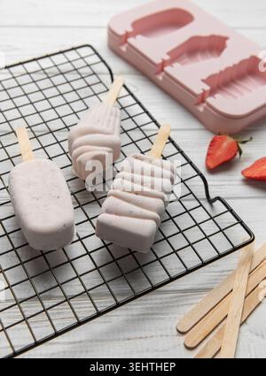 Tre fragole essiccate su una griglia con una muffa rosa e fragole fresche Foto Stock