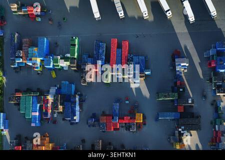 Vista panoramica di un grande e moderno centro di distribuzione. Molti camion parcheggiano presso le banchine di carico. Gli elevatori a forche gestiscono attivamente il carico, mostrando logistica e freschezza Foto Stock
