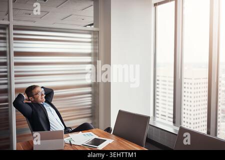 Uomo d'affari, rilassati e allunga con la visione in ufficio per una giornata produttiva o il completamento del lavoro. Uomo, dipendente o riposo con tecnologia o documenti Foto Stock