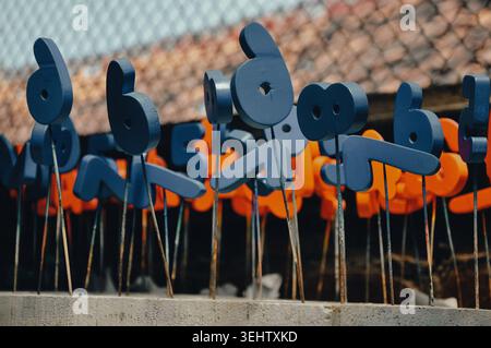 I giocattoli in legno sono montati su aste sottili per la verniciatura. Dipinti in blu e arancione, questi giocattoli ricordano numeri o forme astratte o stilizzate. Foto Stock