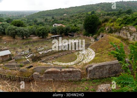 Sessa Aurunca - Campania - Italia - 08-29-2025: Le rovine del teatro romano di Sessa Aurunca si trovano su una collina, con posti a sedere in pietra e mura sparse circondate da verdi alberi e campi. Foto Stock