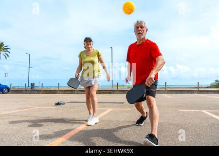 Coppia senior che gioca a picnic su un campo all'aperto vicino alla spiaggia Foto Stock