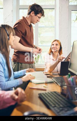 Agenti di supporto che parlano di tablet e servizi client in ufficio Foto Stock