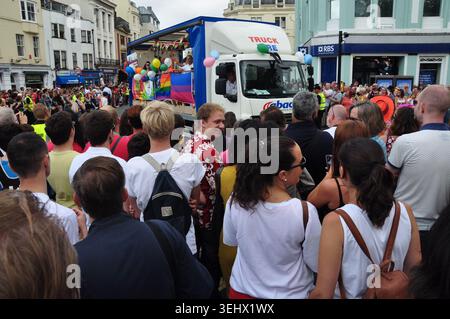 Una grande folla di spettatori si è schierata su una strada della città per guardare un camion decorato del festival passare davanti a un evento di sfilata pubblico Pride. Foto Stock