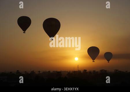 Bellissime mongolfiere che volano attraverso il cielo all'alba sopra Luxor con paesaggi mozzafiato nel deserto e colori vivaci d'atmosfera Foto Stock
