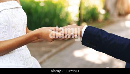 Matrimonio, primo piano e coppia nel parco che tengono per mano il matrimonio, l'amore e l'impegno per la celebrazione. Affetto, all'aperto, sposa e sposo Foto Stock
