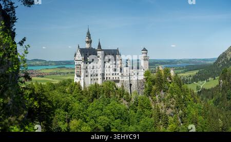 Il fiabesco castello di Neuschwanstein, arroccato su una cresta boscosa, offre viste panoramiche della campagna bavarese, dei laghi e dei campi ondulati Foto Stock