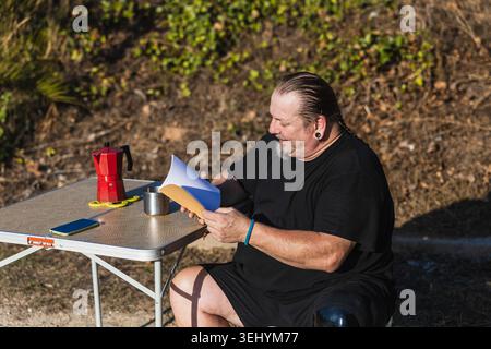 Uomo con una gamba protesica che legge all'aperto bevendo caffè Foto Stock