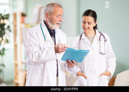 Medici anziani e donne adulte che discutono dei risultati dei test dei pazienti Foto Stock