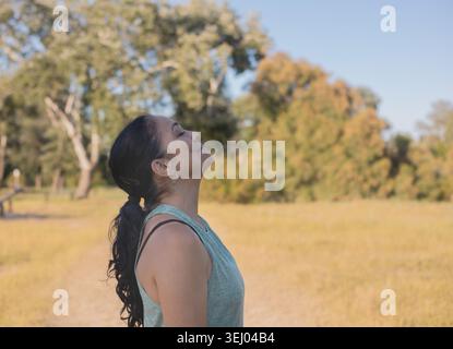 Un ritratto laterale di una donna bruna matura con i capelli in una coda di cavallo, inclinando leggermente la testa all'indietro e chiudendo gli occhi per godere di un soggiorno tranquillo Foto Stock