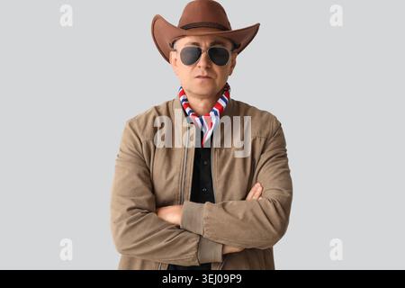 Cowboy maturo in occhiali da sole su sfondo chiaro Foto Stock