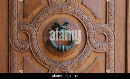 Porta in bronzo antico battente su porta in legno intagliato ornato Foto Stock