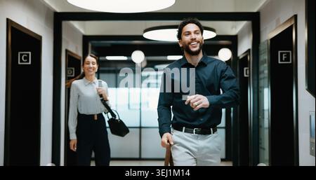Sorridi, cammina o uomo in ufficio con partenza, atteggiamento positivo e buon umore all'uscita dal luogo di lavoro. Pausa, colleghi e dipendenti aziendali con borsa Foto Stock