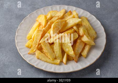 Deliziose patatine fritte e patate fritte fatte in casa servite su un piatto bianco Foto Stock