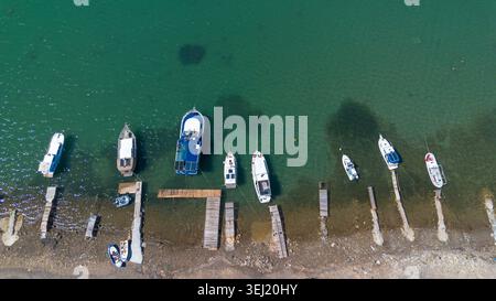 Vista dall'alto del drone aereo delle barche da pesca ormeggiate presso i piccoli moli di legno, Ayvalik - Turchia Foto Stock