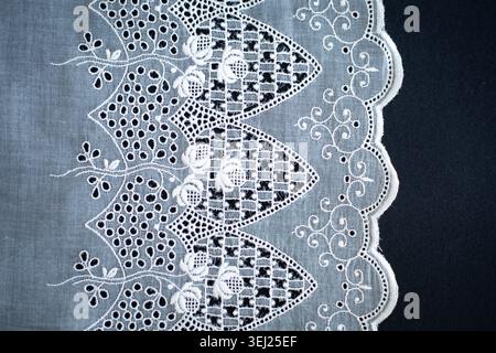Motivo in pizzo, dettaglio di una tovaglia isolata su sfondo nero. Confine artistico. Artigianato, vintage. Concetto di hobby. Vista dall'alto. Foto di alta qualità Foto Stock