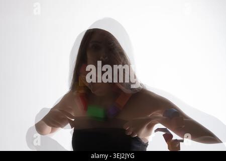 Donna che indossa una collana geometrica dai colori vivaci con effetto spettrale a doppia esposizione Foto Stock