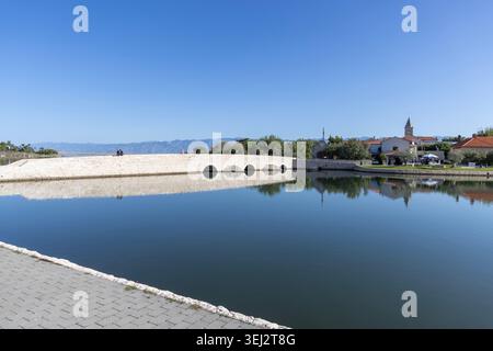 Nin, Croazia, Dalmazia - 15 settembre 2025: Vista panoramica dal lungomare di Branimir del ponte Lower Nin, della porta della città bassa in pietra e della città vecchia Foto Stock