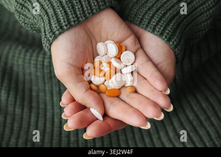 Mani che tengono compresse e capsule medicinali assortite. Medicazione di base che illustra il trattamento farmaceutico e l'uso quotidiano di integratori. Foto Stock
