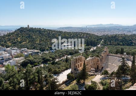 Odeone di Erode Attico e Colle di Filopappo ad Atene, Grecia. Vista dall'alto dell'antico teatro romano, dello skyline della città e del mar Mediterraneo. Foto Stock
