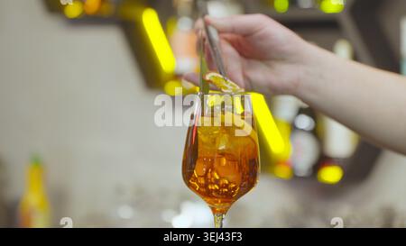 Versare un cocktail arancione in un bicchiere da vicino Foto Stock