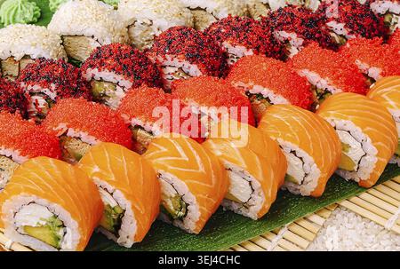 Cibo, Un piatto vivace presenta un assortimento di coloratissimi sushi roll, preparati con cura. I panini includono salmone, avocado e condimenti come il brigh Foto Stock