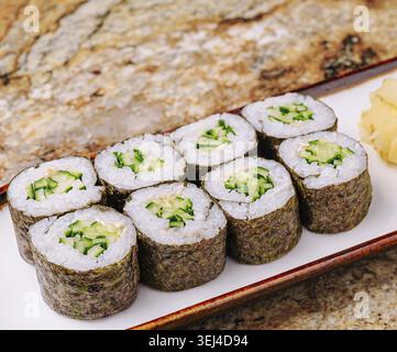 Cibo: Un piatto mostra i panini di sushi al cetriolo appena fatti insieme allo zenzero sottaceto. La preparazione evidenzia il cetriolo verde brillante e l'appe pulito Foto Stock