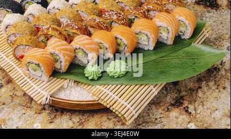 Cibo: Un piatto di sushi ben organizzato offre vari rotoli di sushi colorati preparati con ingredienti freschi. Wasabi e zenzero accompagnano il piatto Foto Stock