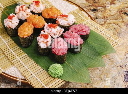 Cibo, un assortimento di sushi su un tappeto decorativo. Il piatto comprende vari tipi di sushi, tra cui gamberi, salmone e tonno, guarnito Foto Stock
