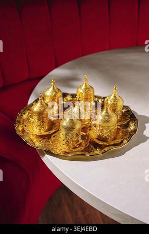Cibo, lussuoso caffè turco decorato con oro sul vassoio. Il vivace sfondo rosso migliora l'aspetto lussuoso, creando un'atmosfera calda e invitante Foto Stock