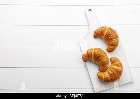 Tradizionale croissant francese su tavolo di legno bianco, gustosa colazione Foto Stock