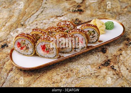 Cibo, deliziosi sushi roll sono presentati su un lungo piatto bianco, guarniti con wasabi e zenzero sottaceto. Questi rotoli sono caratterizzati da ingredienti colorati e. Foto Stock
