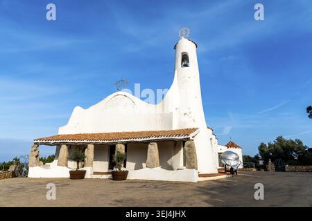 Vista frontale della Chiesa Stella Maris a Porto Cervo con pareti bianche, colonne in pietra e un piccolo campanile sotto un cielo azzurro Foto Stock