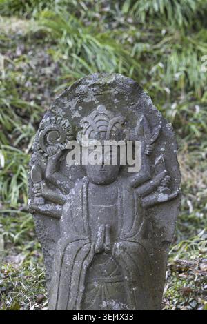 Piccola placca scultorea di Buddha con la figura di Murti, diversi volti e braccia che simboleggiano diversi poteri nel tempio Saigandenji nel piccolo villag Foto Stock