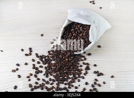 Chicchi di caffè tostati e borsa di tela sul tavolo della cucina. Vista dall'alto Foto Stock