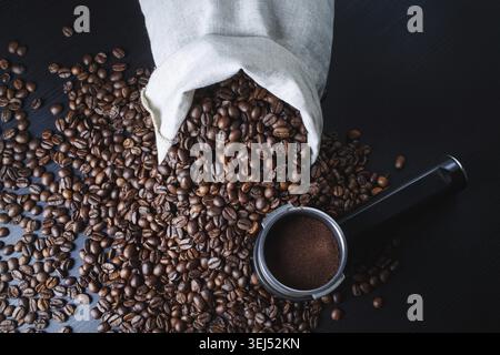Chicchi di caffè tostati, borsa in tela e supporto da una macchina espresso sul tavolo della cucina. Vista dall'alto Foto Stock