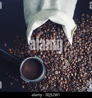 Chicchi di caffè tostati, borsa in tela e supporto della macchina espresso sul tavolo della cucina. Vista dall'alto Foto Stock