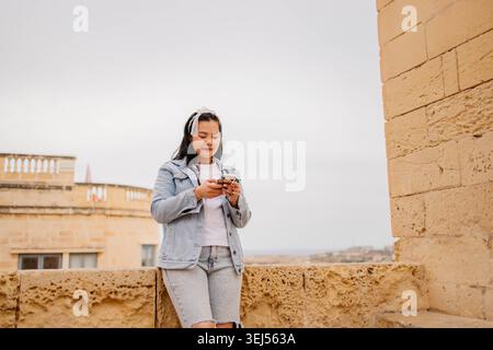 Donna che usa il telefono nella città vecchia Foto Stock