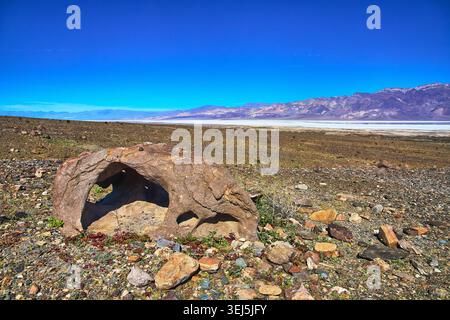 Roccia con il buco naturale e ampio paesaggio del deserto sotto il cielo blu Foto Stock