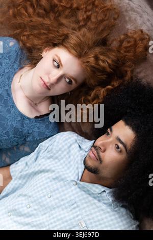 Coppia giovane e variegata che si rilassa, condivide un momento intimo e guarda lontano Foto Stock