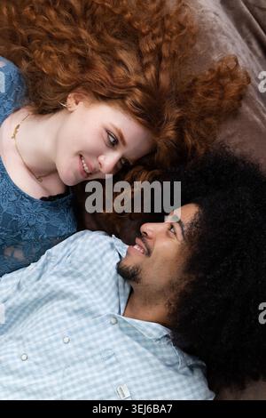 Giovane felice coppia interrazziale sorridente e guardante l'un l'altro Foto Stock