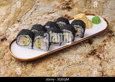 Cibo, Una selezione di sushi roll è disposta ordinatamente su un piatto bianco. I panini presentano riso nero e vivaci ripieni, tra cui gamberi e vegetale Foto Stock