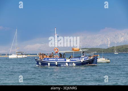 Nydri - Isole Ionie - Grecia - 08-07-2025: Una barca passeggeri piena di persone naviga attraverso il mare blu vicino a Lefkas, con montagne e altre ve Foto Stock