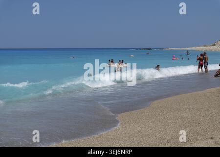 Nydri - Isole Ionie - Grecia - 08-09-2025: Persone che si godono le onde turchesi del mare su una spiaggia sabbiosa, alcune nuotano e altre si trovano vicino al litorale Foto Stock