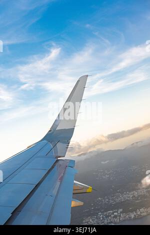 Volo aereo sopra Corfù, Grecia, contro un cielo blu con nuvole sparse e un sole Foto Stock