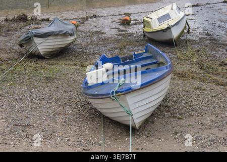 un primo piano di tre piccole barche ormeggiate sulla spiaggia mentre la marea è uscita. C'è spazio di copia all'interno dell'immagine Foto Stock