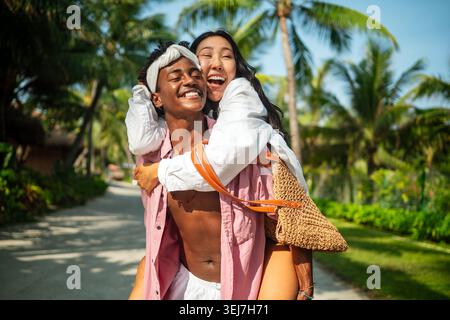 Felice coppia interrazziale che abbraccia e condivide un momento romantico durante una fuga sull'isola tropicale Foto Stock